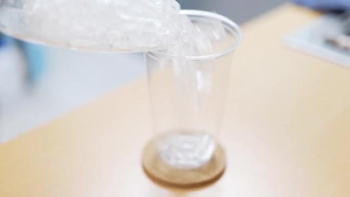 将冰块倒入塑料玻璃杯中。