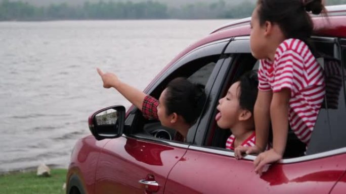 快乐的家庭在暑假享受公路旅行。母亲和孩子们都很兴奋，喜欢开车旅行，看着窗外。假日和旅游家庭概念。