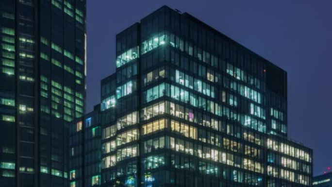 市区商务中心大楼白天到黑夜过渡闪烁的办公室窗户灯。公司业务，高摩天大楼玻璃表面。建筑窗户中的灯打开和