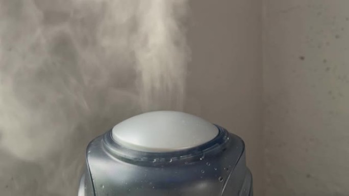 加湿器在灰色墙壁背景上工作。来自加湿器的水雾蒸汽。