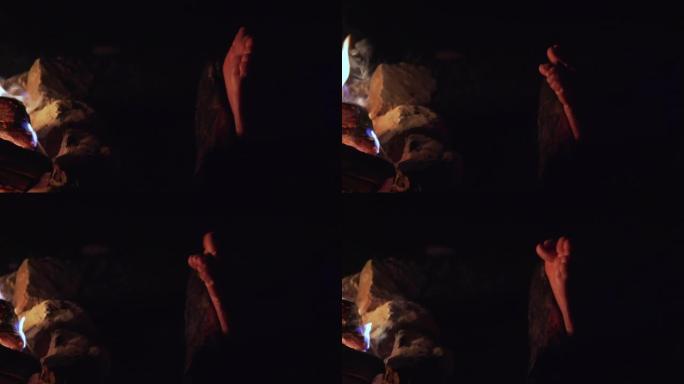 女性晚上在篝火旁晒脚
