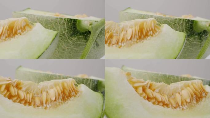 绿色甜瓜或哈密瓜切片，种子在白色背景上。