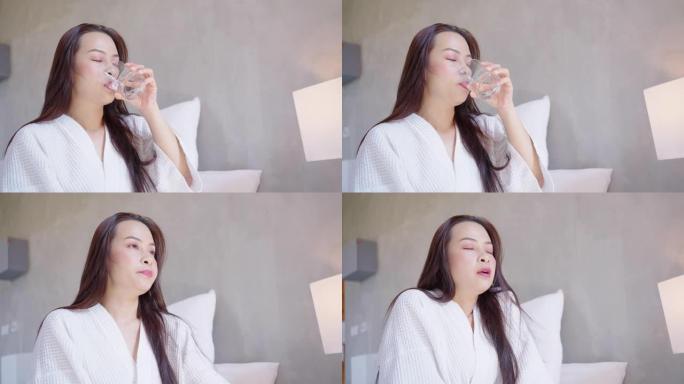 亚洲妇女醒来并在卧室里喝水的特写镜头
