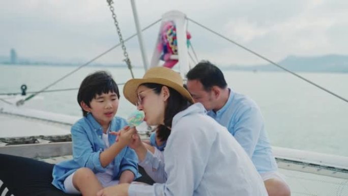 有两个孩子的亚洲家庭在游艇上玩得很开心。