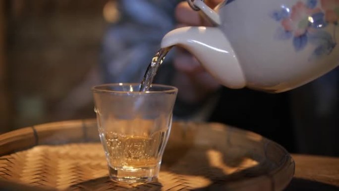 慢动作的茶被倒入茶杯上的老式餐桌上，热饮饮料提神茶的时间。