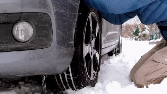 汽车被困在雪地里，人不能在轮胎上放防滑链