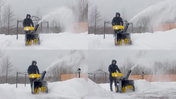 一名男子在院子里用吹雪机在慢动作降雪时清理积雪。前视图。慢动作
