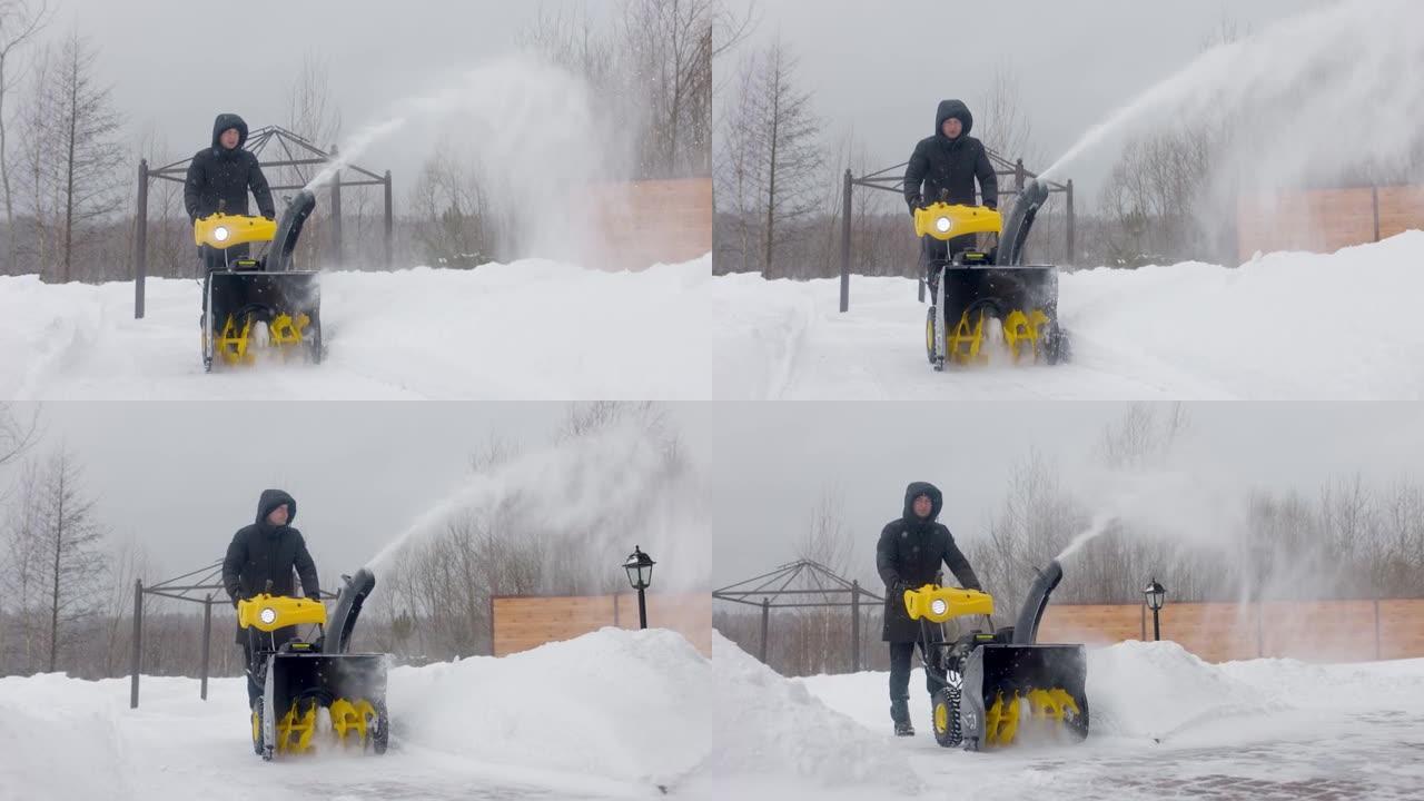 一名男子在院子里用吹雪机在慢动作降雪时清理积雪。前视图。慢动作