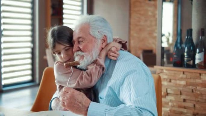 小女孩在午餐时拥抱她快乐的祖父