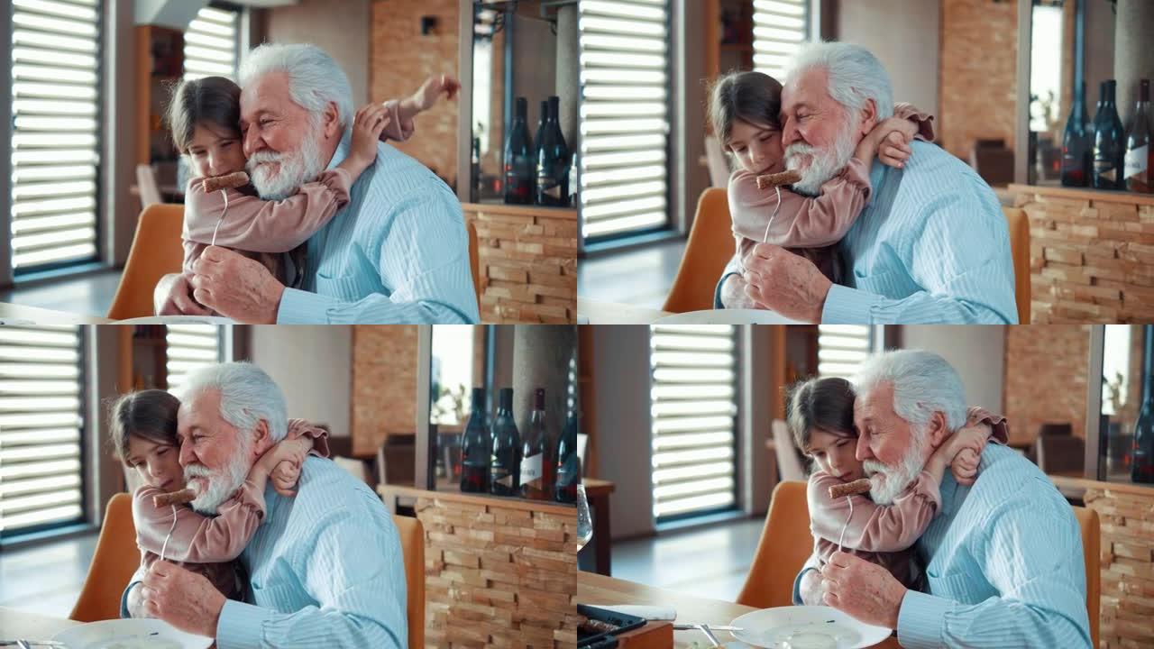 小女孩在午餐时拥抱她快乐的祖父