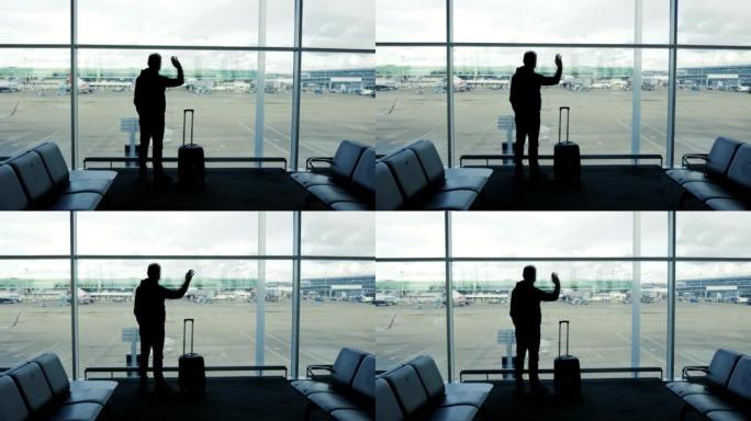 中年男子在机场向窗户挥手告别，旅行概念，