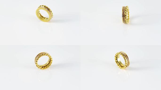 旋转金色打结闪闪发光的双金戒指，白色背景上有锆石。美丽的情人节礼物。