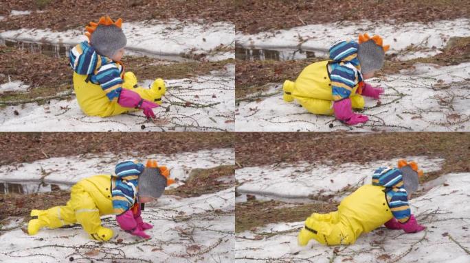 黄色防水雨裤围兜的孩子在寒冷的季节散步，一岁的男婴在阳光明媚的冬日在雪地里玩耍。