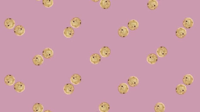 在粉红色的背景上旋转新鲜巧克力饼干的彩色图案。无缝模式与饼干。前视图。现实的动画。4 k视频运动