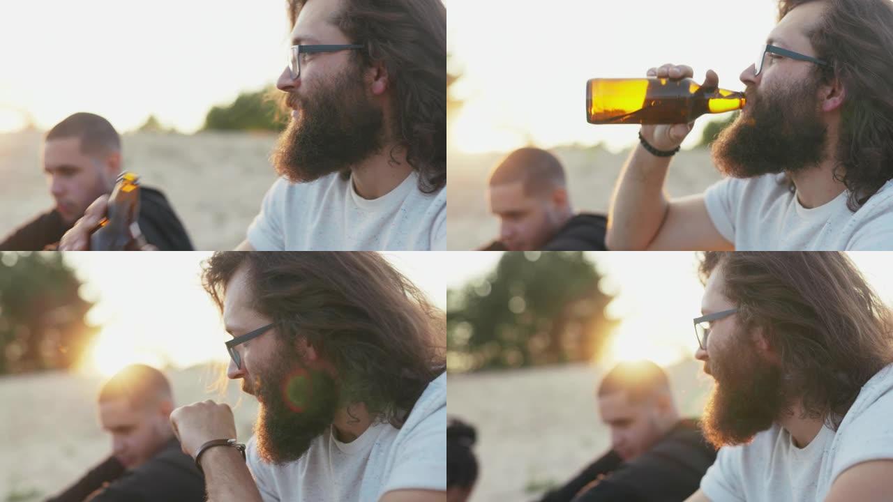 在侧面可以看到一个戴着眼镜的长发和浓密胡须的男人的脸男孩正在从玻璃瓶中喝啤酒，并与坐在外面的背景光线