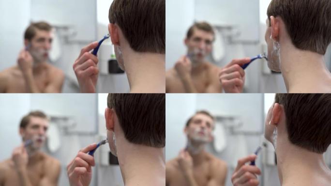 一个男人的后脑勺特写照着浴室的镜子，洗完澡后剃了脸，一个一千岁的男人照顾他的胡茬或胡须，在洗澡时做了