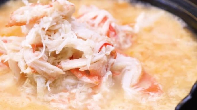 螃蟹粥的特写视频。蟹肉和鸡蛋放在火锅汤里的菜。