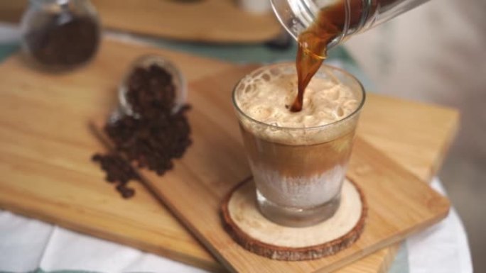 将泡沫和奶油咖啡混合的冷牛奶倒入玻璃杯中。冰咖啡拿铁。Tik tok趋势达尔戈纳咖啡准备饮用。