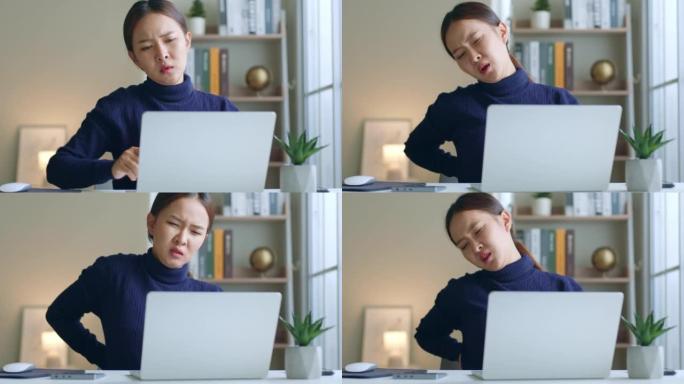 疲倦的年轻亚洲妇女在努力工作笔记本电脑时腰酸背痛，办公室综合症