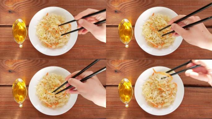 手里拿着亚洲筷子吃酸菜。酸菜胡萝卜发酵乳酸菌蔬菜酸味健康地方食品维生素c美味菜单国欧菜