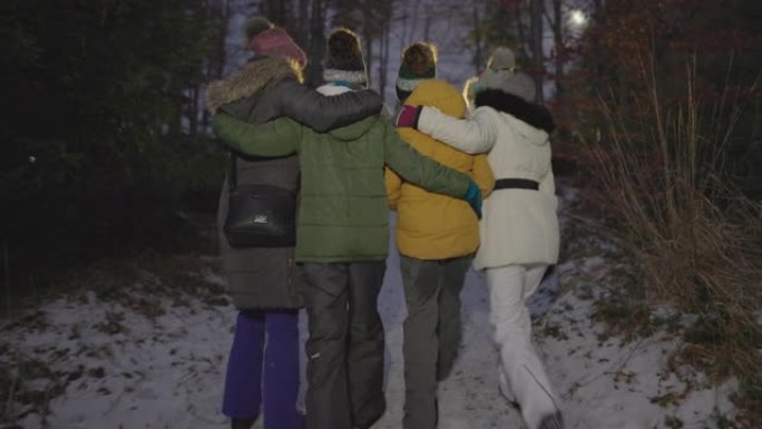 母亲和三个孩子晚上在冬天的森林里散步