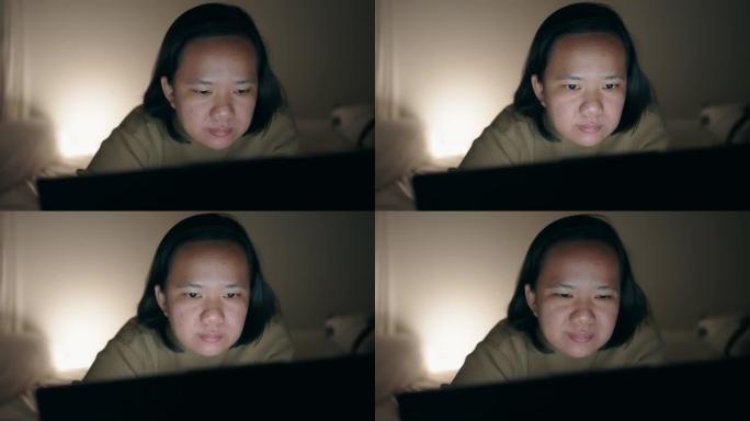 亚洲女子晚上躺在床上用笔记本电脑看电影