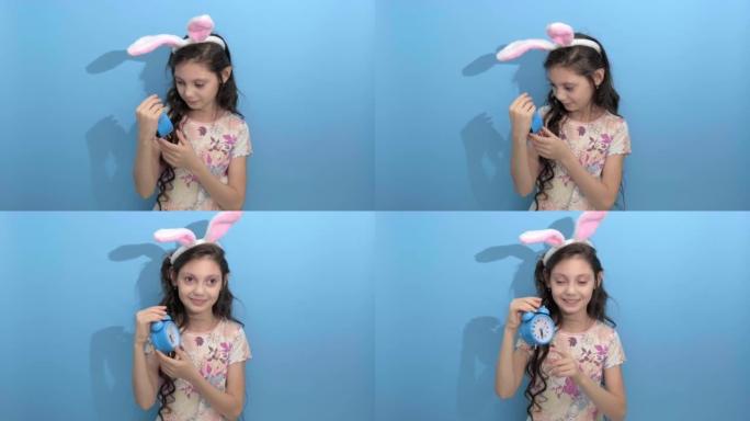 复活节快乐。复活节兔子耳朵里美丽可爱的女孩拿着闹钟
