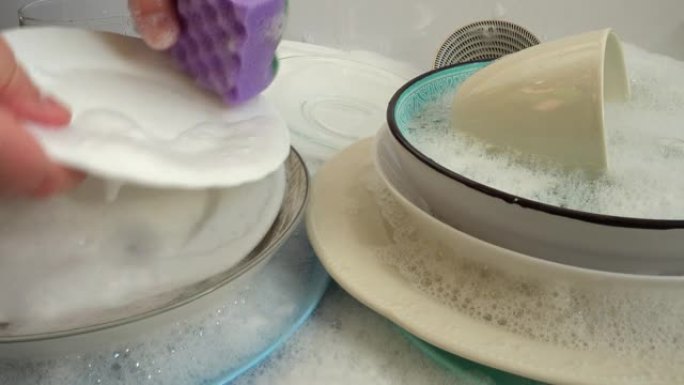 一个女人用肥皂毛巾洗碗。