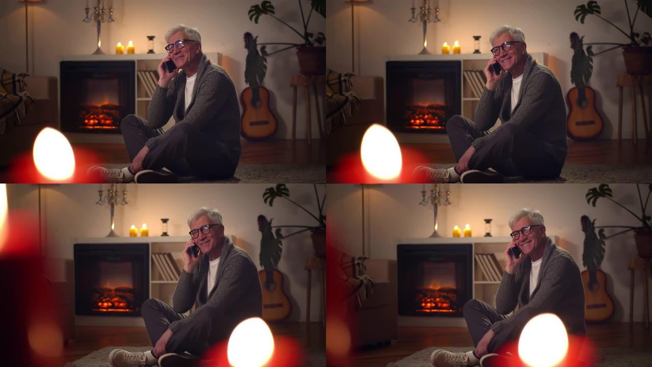 快乐的白人老人在手机上聊天，微笑着坐在壁炉旁