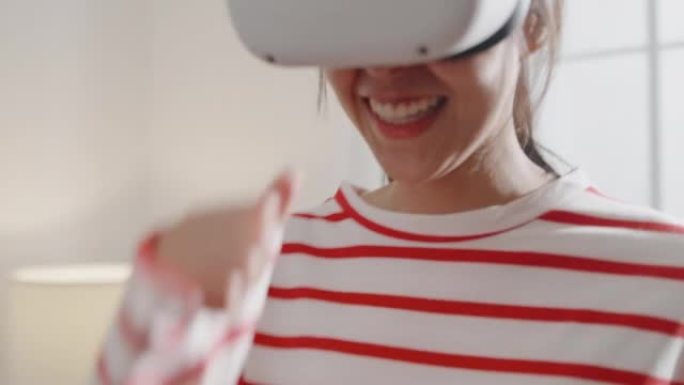 年轻女子的特写佩戴VR耳机获得体验模拟数字世界跑步游戏动作模拟器游戏手机应用程序在家里的客厅。