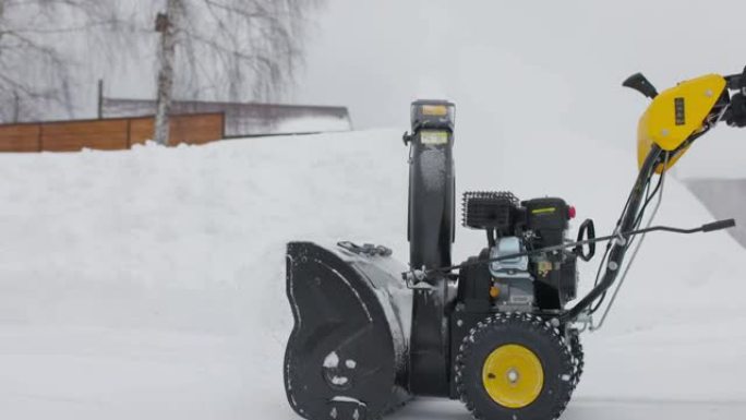 大雪过后，男人用木屋的扫雪机清理积雪。前视图。慢动作