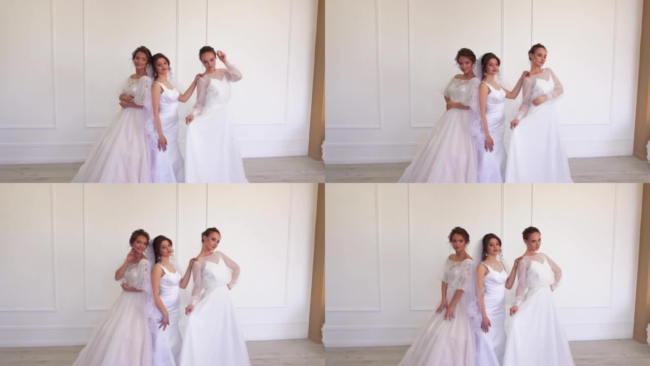 三个穿着白色连衣裙的黑发漂亮新娘正站着摆姿势。