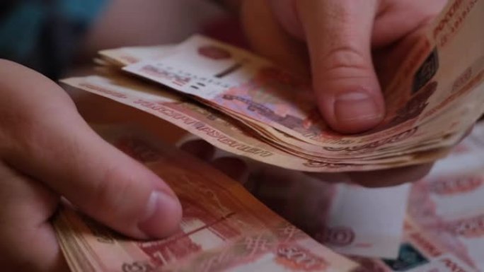 男性手数俄罗斯的钱5000钞票的背景旋转一堆钱