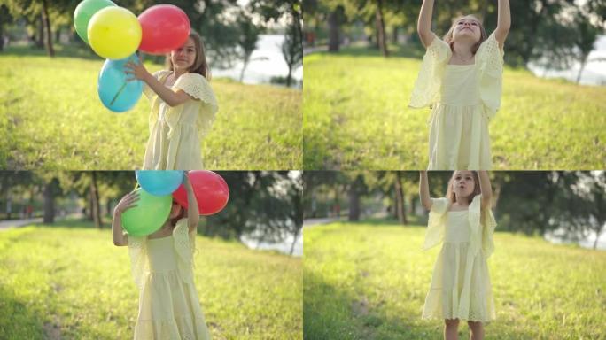 春夏公园阳光明媚的日子里，积极的女孩玩五彩气球。穿着黄色连衣裙的快乐黑发白人儿童在户外享受休闲的肖像