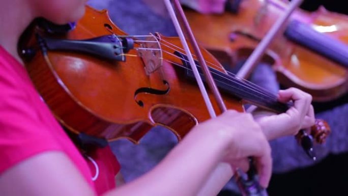 小提琴和带弓的手的特写镜头。交响乐团。小提琴家的表演。古典音乐