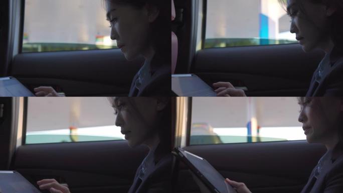 一名中年女商人在汽车后座上使用数字平板电脑
