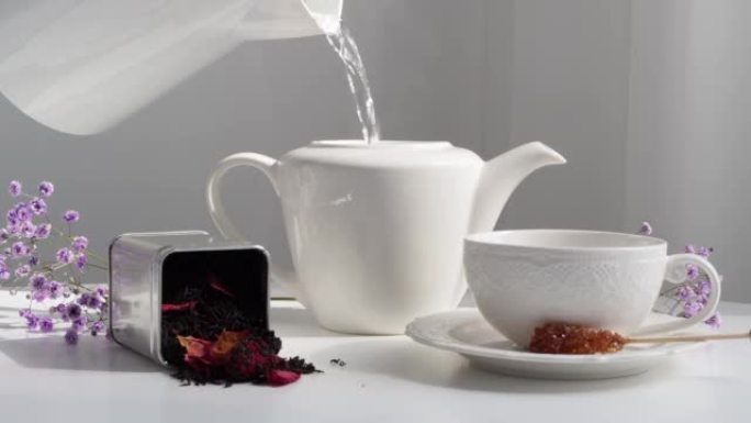 将热水倒入白色茶壶中。接待客人的桌子设置。酿造红茶。HLS。不含咖啡的早餐