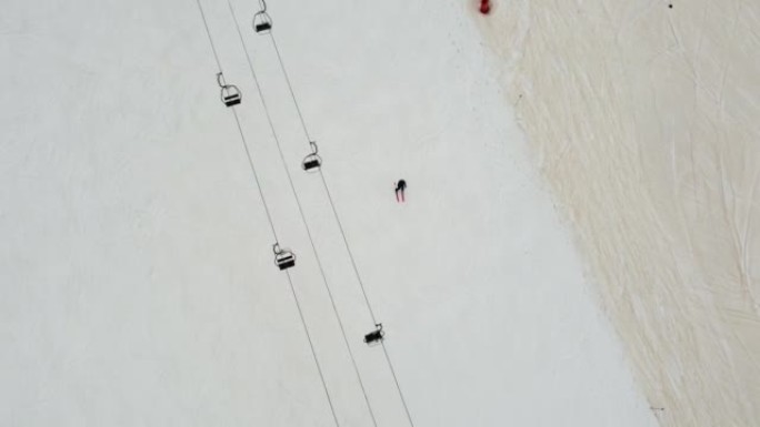 单人滑雪者在滑雪缆车下沿着滑雪坡走下的俯视图