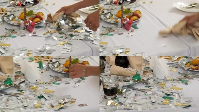 第一次婚礼舞会后，女服务员从桌子上清除了银色的五彩纸屑。有史以来最好的一天。