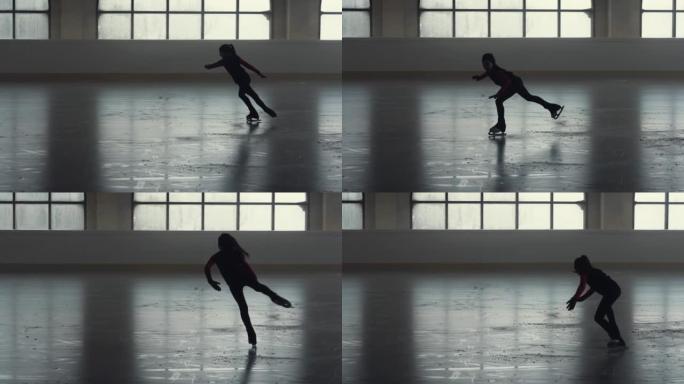 花样滑冰训练。小女孩花样滑冰运动员正在用一条腿滑冰练习旋转技巧。柔和光线的黑暗冰上舞台上的花样滑冰编