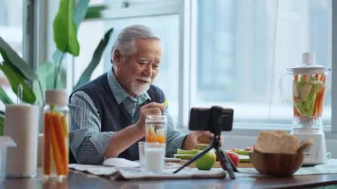 亚洲老年男性vlog在手机上教烹饪。男老人vlogs，老厨师在手机上录制了有关在家准备健康沙拉和注入