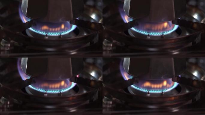 蓝色的火焰在炉子上燃烧丁烷气体，上面装有咖啡机，火焰在最后脱落