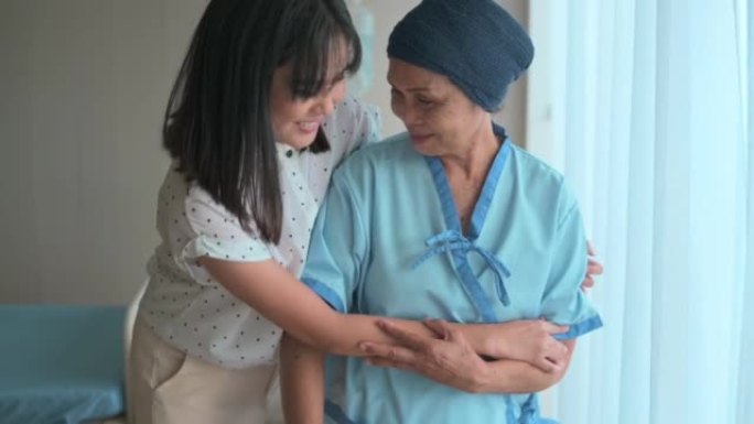 癌症患者妇女戴着头巾和她的支持女儿在医院，健康和保险的概念