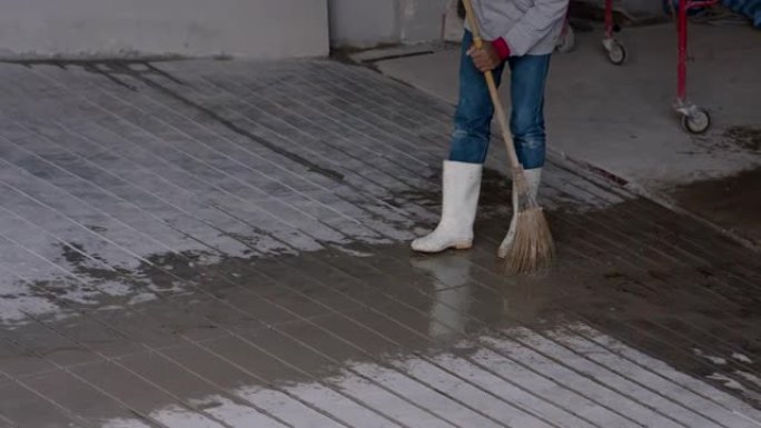 4K，施工人员在完成道路后，使用椰子扫帚在停车场的混凝土地板上扫除污垢