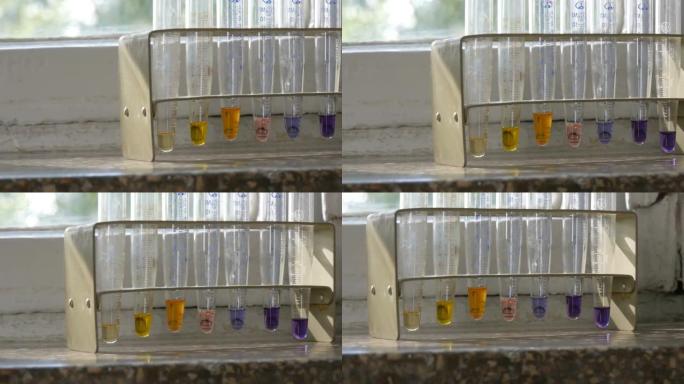 在带有大理石窗台的旧窗户上的实验室中，医用试管中的彩色液态水。