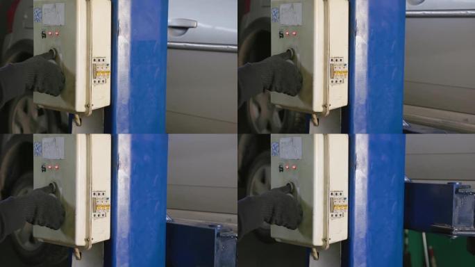 工人在服务站汽车修理厂车库的电梯上戴着黑色手套，在银色轿厢上。汽车服务、维修和保养的概念。