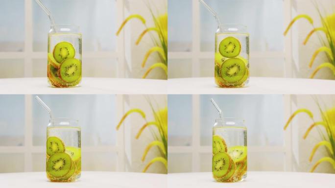 由新鲜猕猴桃在玻璃罐中制成的排毒饮料，吸管在苏打水中，在浅色背景上在白色桌子上旋转。莫吉托水果鸡尾酒