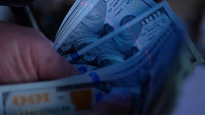 紫外线下的美元钞票。概念-检查美元的真实性。在钞票上搜索水印。
