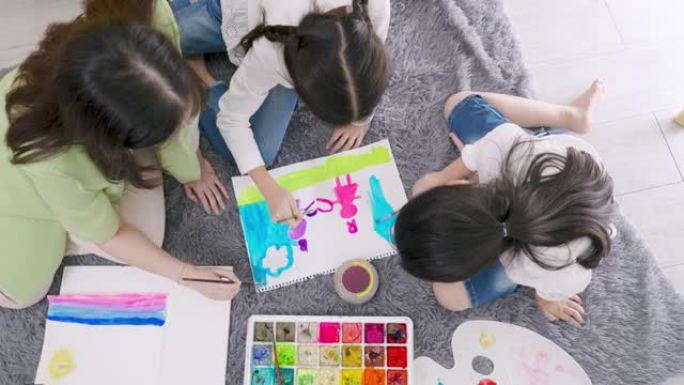 两个小孩的俯视图在白色画纸上的中间水彩画中牵着心连心，用水彩画画和创造了美丽的年轻亚洲教师女人和两个