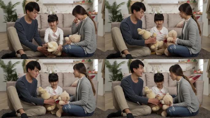 亚洲爸爸和妈妈在客厅里的地板上假装和他们的女学生玩得开心。他们抱着毛绒熊和兔子在家聊天